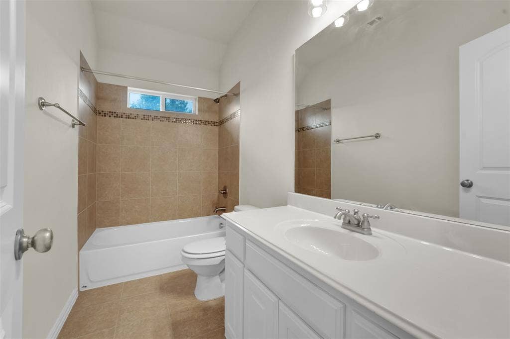 6811 Shady View Court, Sachse, TX 75048 Bathroom featuring a vanity with an integrated sink, a large wall-mounted mirror, and a tub with tiled surround