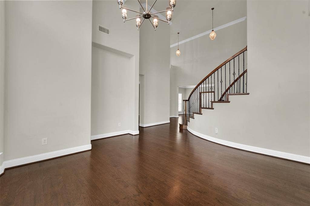 6811 Shady View Court, Sachse, TX 75048 Dark wood-finish flooring, a curved staircase with wrought iron balusters, high ceilings, and crown molding