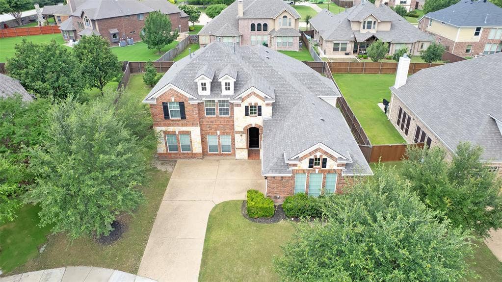 6811 Shady View Court, Sachse, TX 75048 Brick and stone facade, dormer windows, attached two-car garage, concrete driveway, and mature landscaping