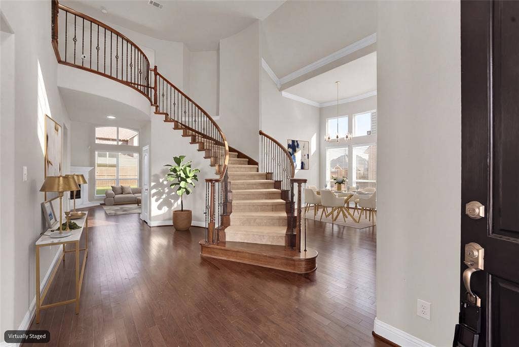 6811 Shady View Court, Sachse, TX 75048 Grand foyer featuring a curved staircase with wrought iron balusters and wood handrails, hardwood flooring, and tall windows