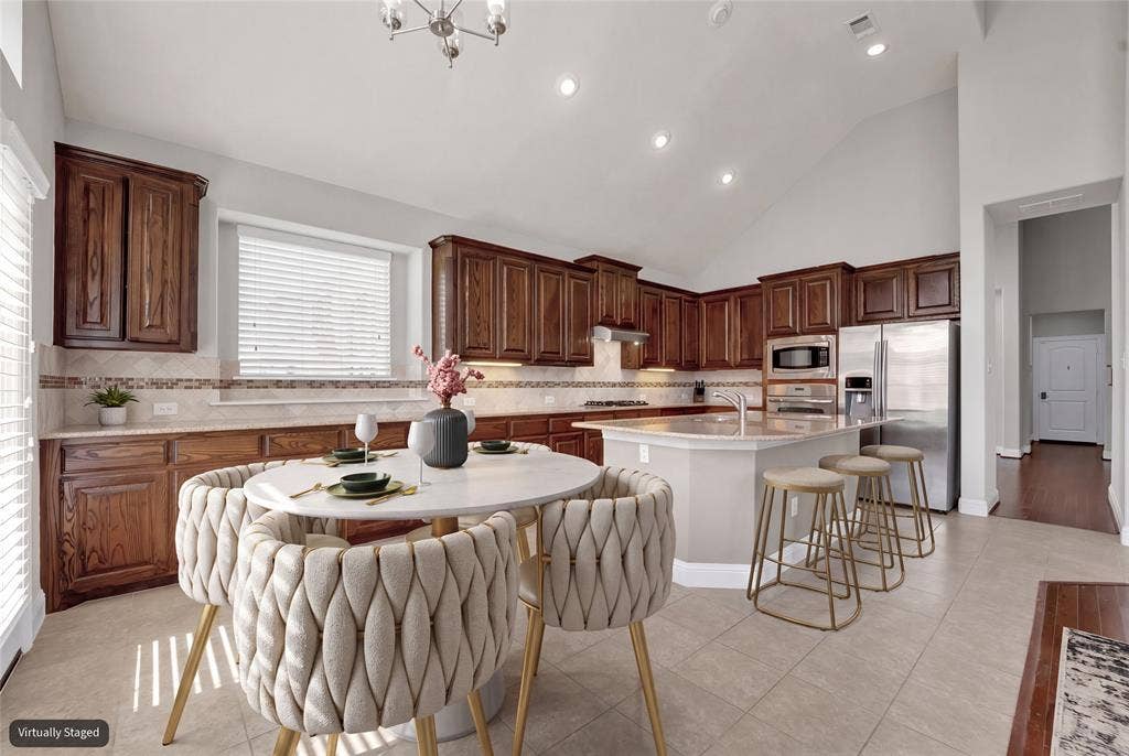 6811 Shady View Court, Sachse, TX 75048 Spacious kitchen with vaulted ceilings, recessed lighting, wood cabinetry, stainless steel appliances, and a central island with bar seating