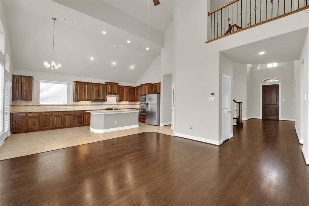 6811 Shady View Court, Sachse, TX 75048 Two-story ceiling, recessed lighting, wood-finish flooring, wood cabinetry, and a kitchen island
