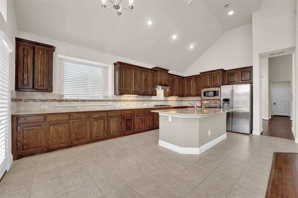 6811 Shady View Court, Sachse, TX 75048 Vaulted ceilings, recessed lighting, wood-finish cabinetry, stainless steel appliances, and a central island with sink