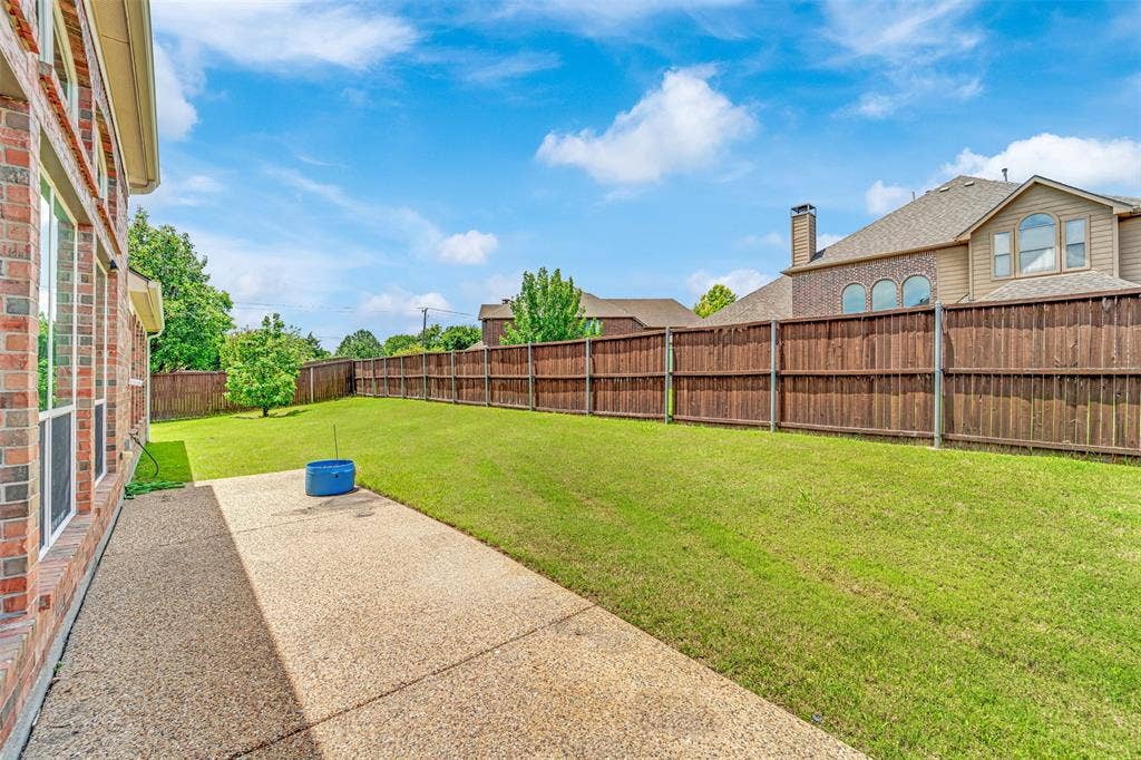 6811 Shady View Court, Sachse, TX 75048 Expansive green lawn, wood privacy fencing, concrete patio, and brick exterior with multiple windows