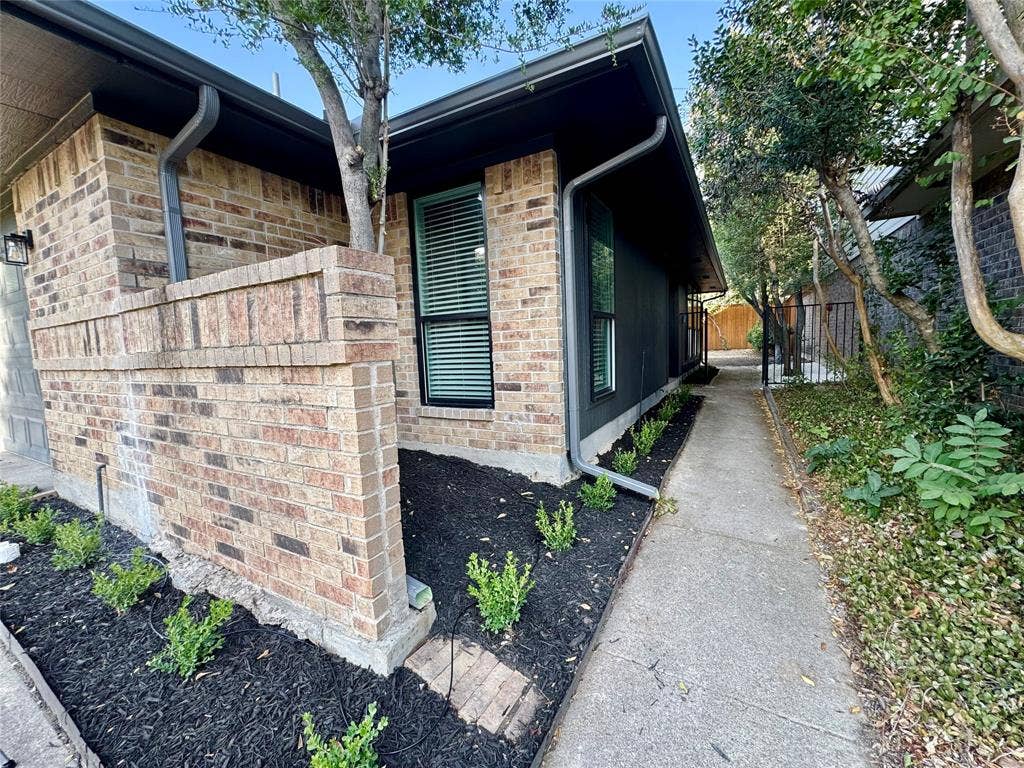 3706 Aries Drive, Garland, TX 75044 Brick facade with dark trim, featuring a concrete walkway and landscaped beds with young plantings