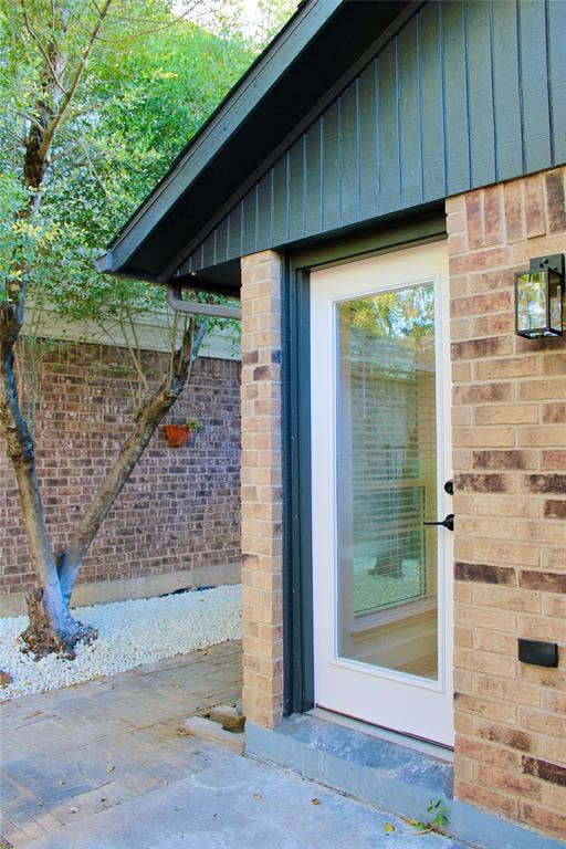 3706 Aries Drive, Garland, TX 75044 Brick exterior with board and batten siding, outdoor lantern-style lighting, and a full-light door