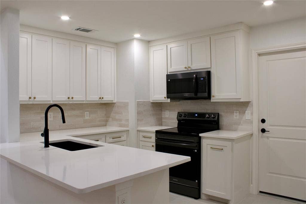 3706 Aries Drive, Garland, TX 75044 Kitchen featuring white shaker-style cabinetry, light-toned tiled backsplash, white countertops, a large black sink with a matte black faucet, and black appliances