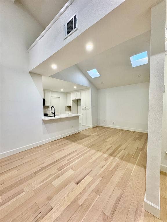 3706 Aries Drive, Garland, TX 75044 Wood-finish flooring throughout, vaulted ceiling, two skylights, recessed lighting, and a kitchen featuring white cabinetry