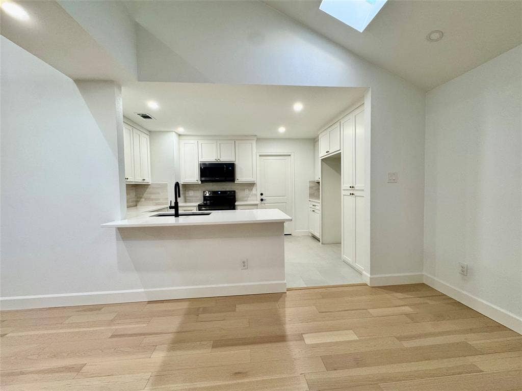 3706 Aries Drive, Garland, TX 75044 Open concept kitchen with white cabinetry, built-in appliances, a breakfast bar, and wood-finish flooring
