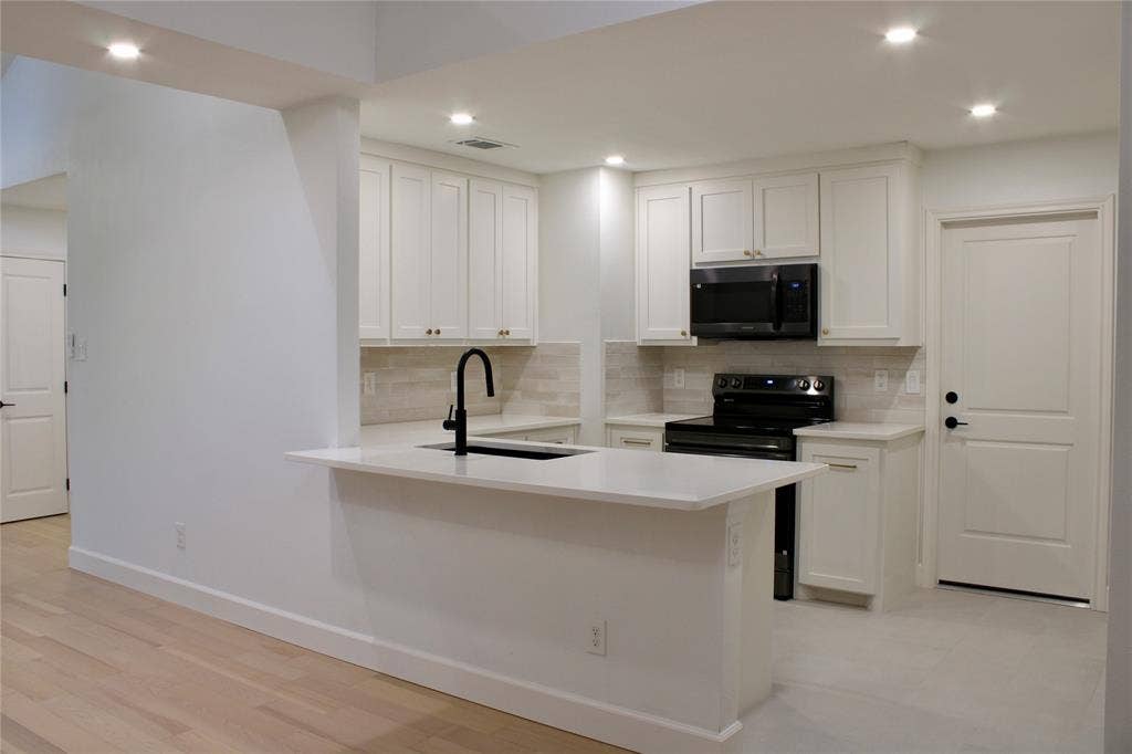 3706 Aries Drive, Garland, TX 75044 Kitchen featuring white cabinetry, light countertops, a black range, a black microwave, and recessed lighting