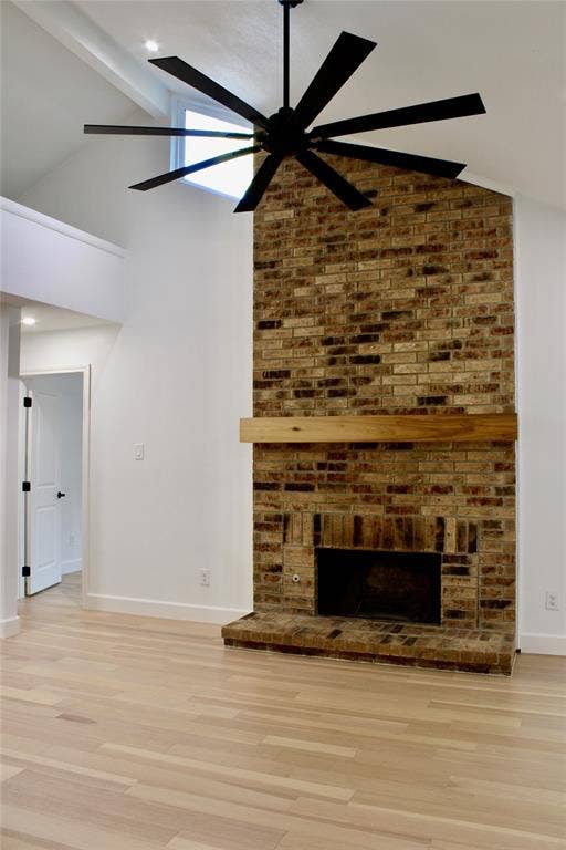 3706 Aries Drive, Garland, TX 75044 Brick-clad fireplace with a wood mantle, vaulted ceiling with an exposed beam, and a multi-blade ceiling fan
