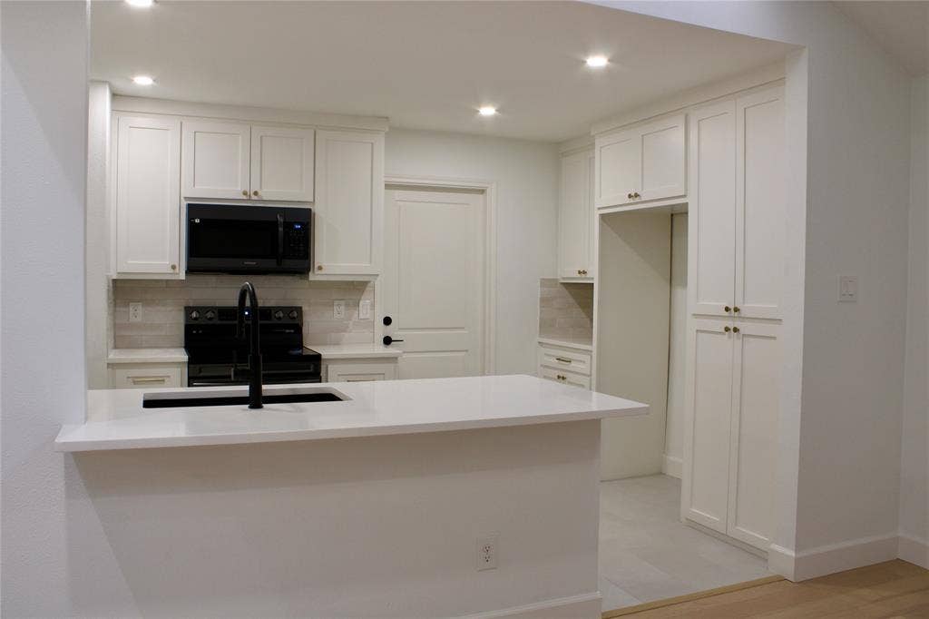 3706 Aries Drive, Garland, TX 75044 Kitchen featuring white shaker cabinetry, an integrated kitchen island with a dark basin sink, black appliances, recessed lighting, and tile flooring