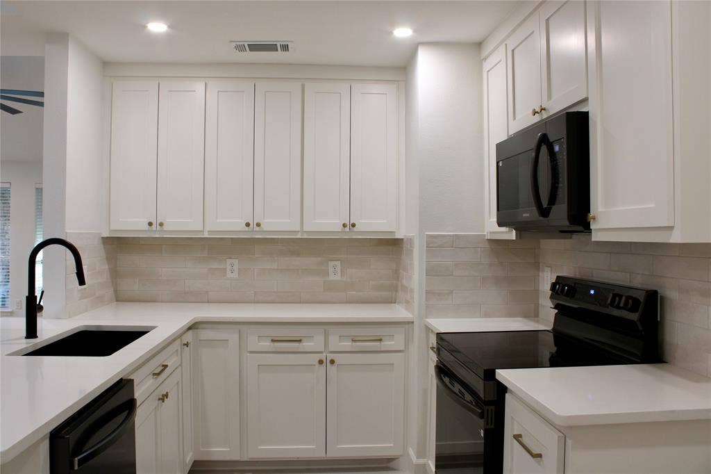 3706 Aries Drive, Garland, TX 75044 White shaker cabinetry, light-toned backsplash, black appliances, solid surface countertops, and recessed lighting