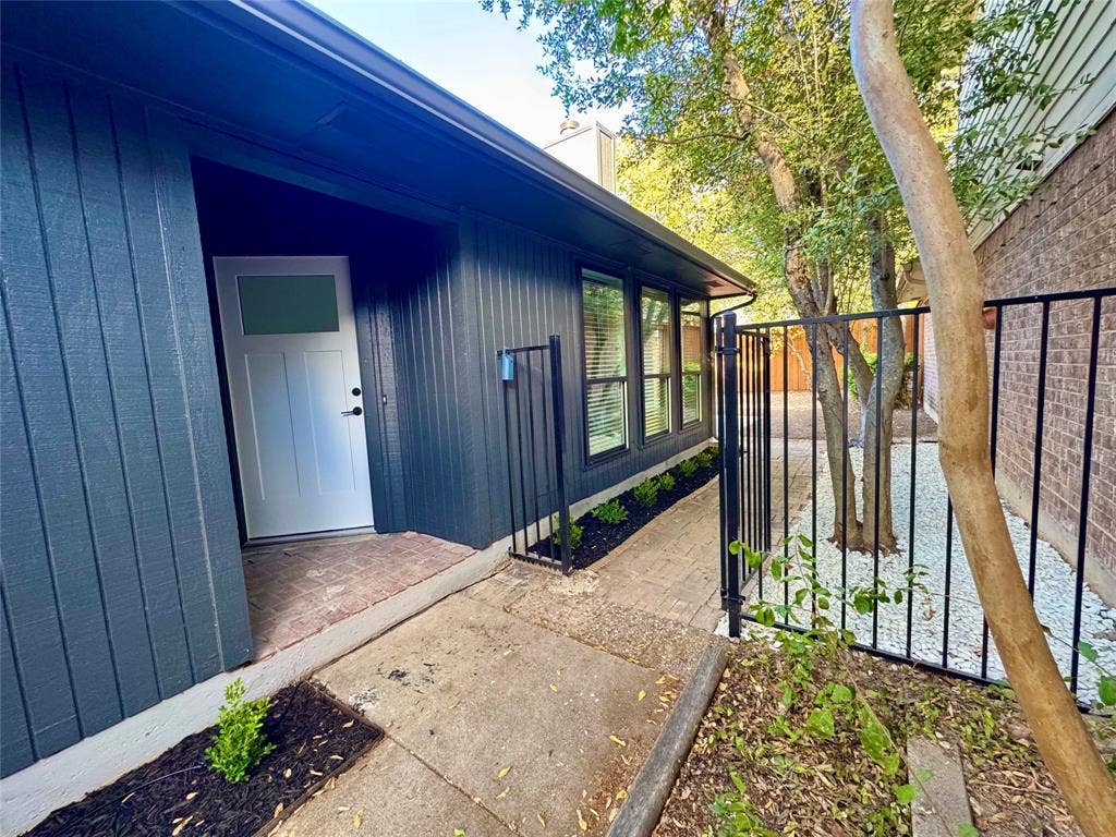 3706 Aries Drive, Garland, TX 75044 Vertical siding exterior with a white entry door, multiple windows, and a black wrought iron fence