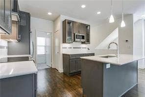 4303 Cole Avenue, #17, Dallas, TX 75205 Kitchen featuring dark wood-finish cabinetry, light countertops, an integrated microwave, and a center island with a sink and pendant lighting