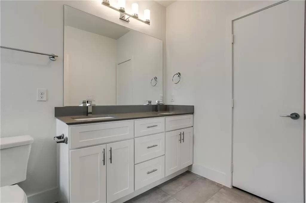 4303 Cole Avenue, #17, Dallas, TX 75205 Dual vanity with a dark countertop, white shaker-style cabinetry, and integrated sinks