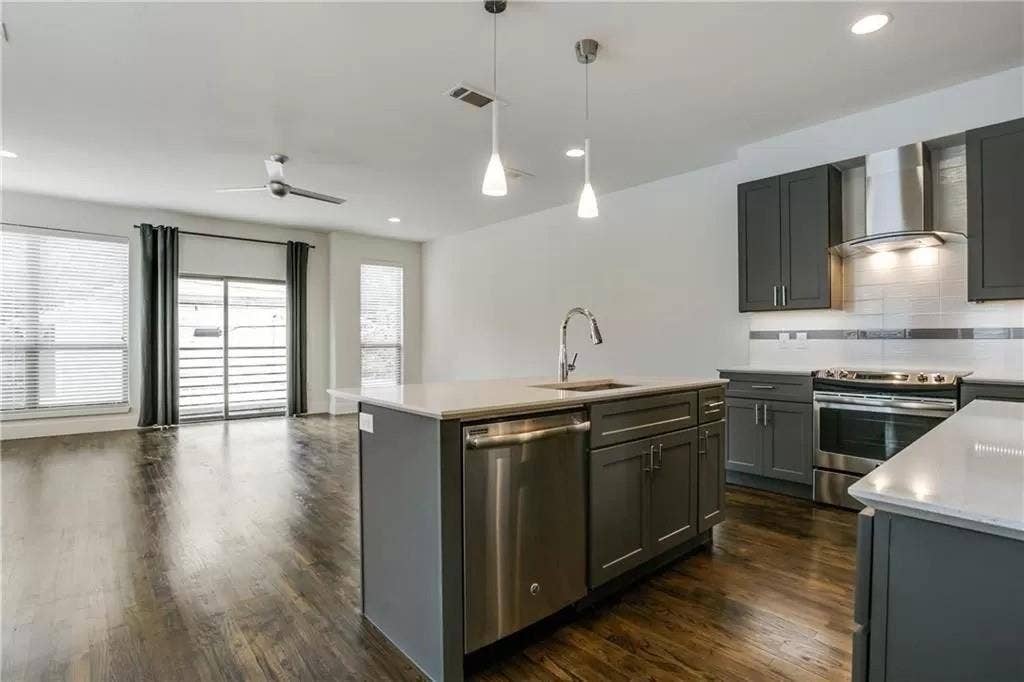 4303 Cole Avenue, #17, Dallas, TX 75205 Dark wood-finish flooring throughout, complemented by a modern kitchen featuring stainless steel appliances, dark gray cabinetry, and light countertops