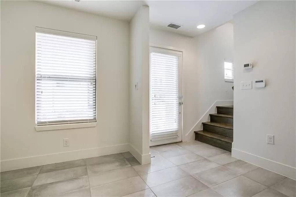 4303 Cole Avenue, #17, Dallas, TX 75205 Ceramic tile flooring, white walls, window with blinds, door with blinds, and wood-finish staircase