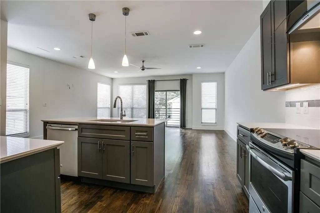 4303 Cole Avenue, #17, Dallas, TX 75205 Kitchen island with built-in sink and stainless-steel dishwasher, complemented by wood-finish flooring, recessed lighting, and pendant light fixtures