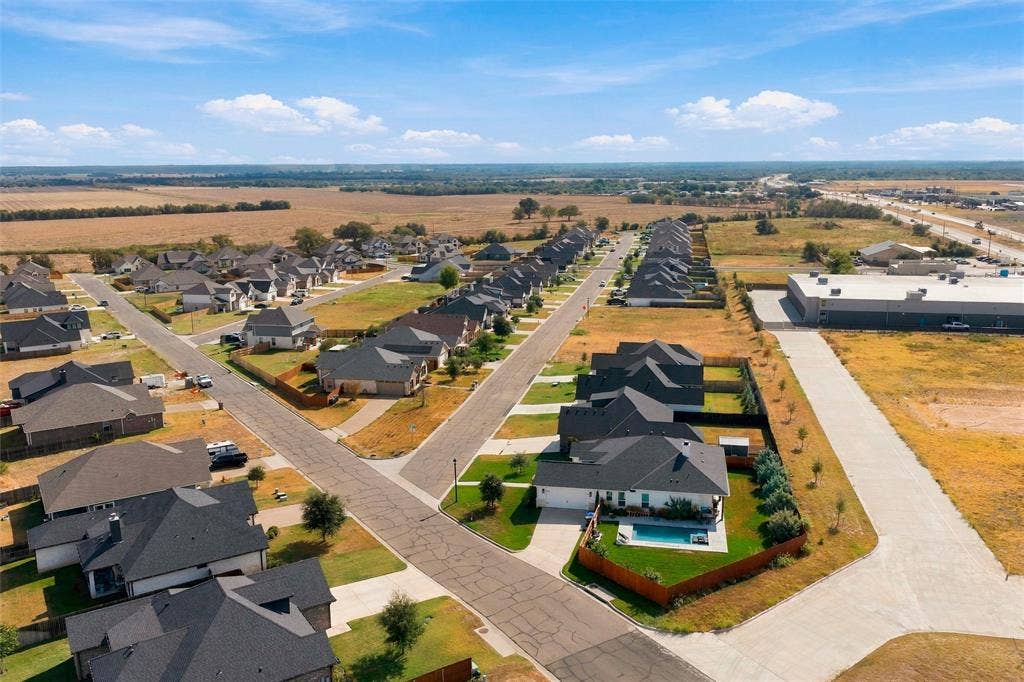 9924 Bridlewood Lane, Waco, TX 76708 Aerial perspective of a developed residential area with multiple residences, a commercial structure, and roadways, bordered by undeveloped land
