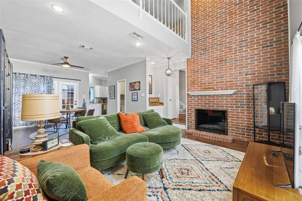 Two-story living area featuring a brick fireplace with a mantel, recessed lighting, and wood-finish flooring