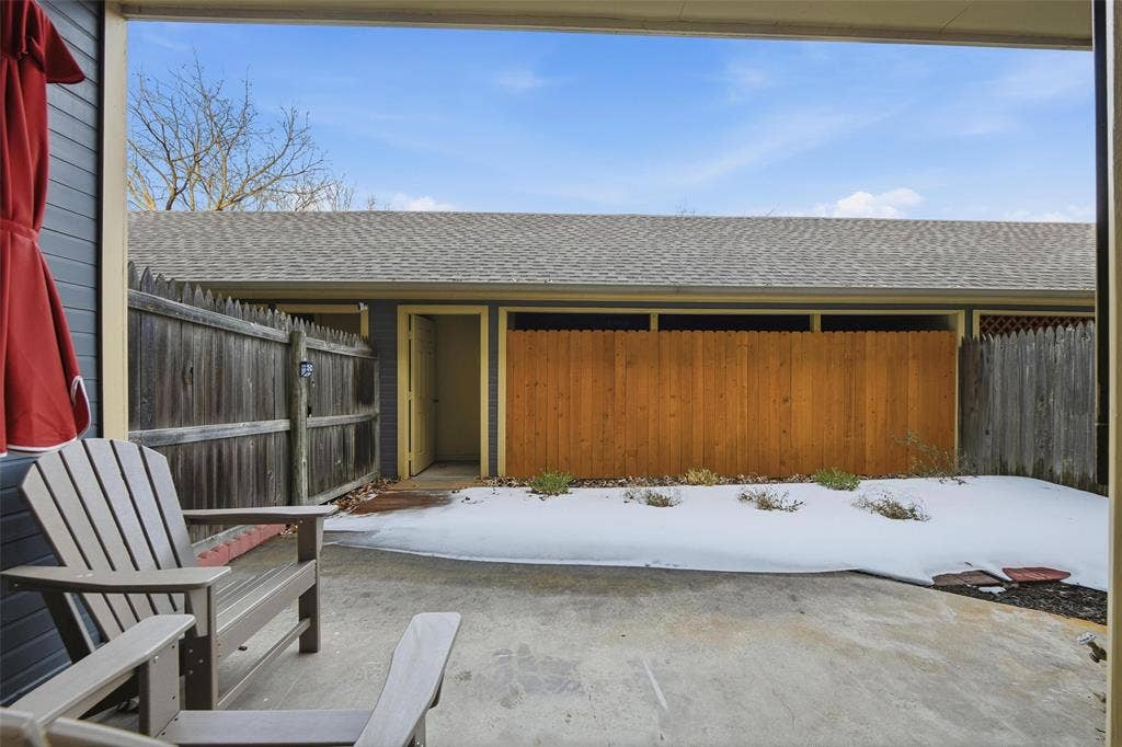 Concrete patio with a wooden privacy fence and a composition shingle roof