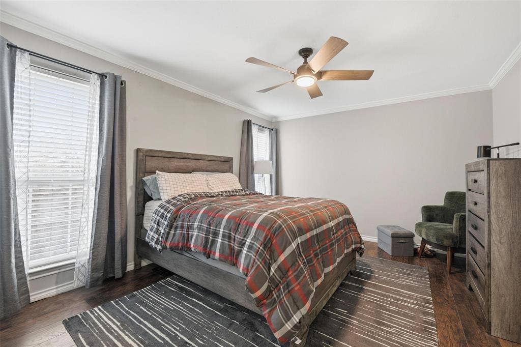 Crown molding, wood-finish flooring, ceiling fan with integrated lighting, window with blinds, and neutral wall tones