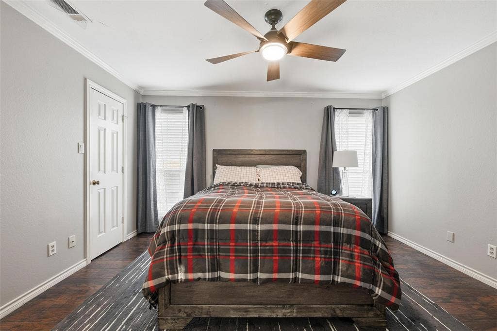 Wood-finish flooring, crown molding, and a wood-bladed ceiling fan with integrated lighting