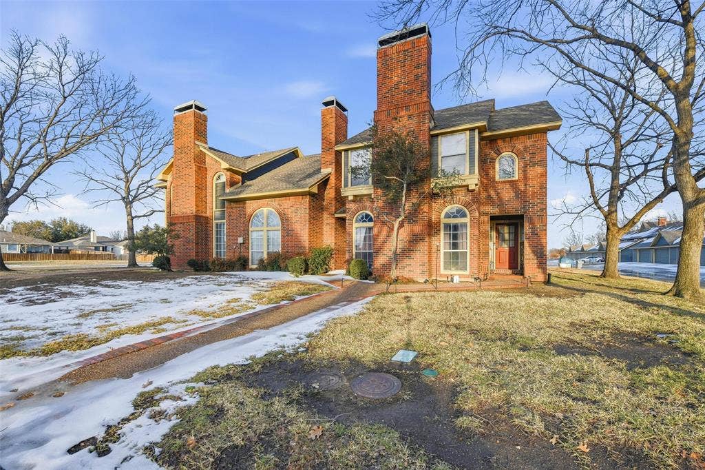 Brick exterior with multiple prominent chimneys, arched windows, and an arched entry door