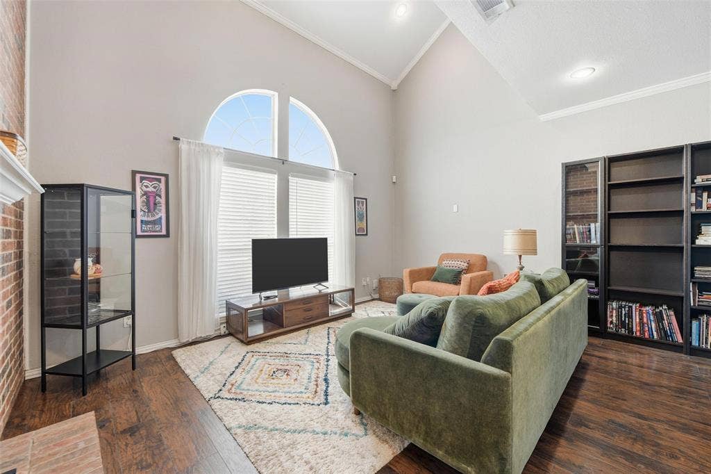 Vaulted ceilings, wood-finish flooring, and a large arched window with blinds