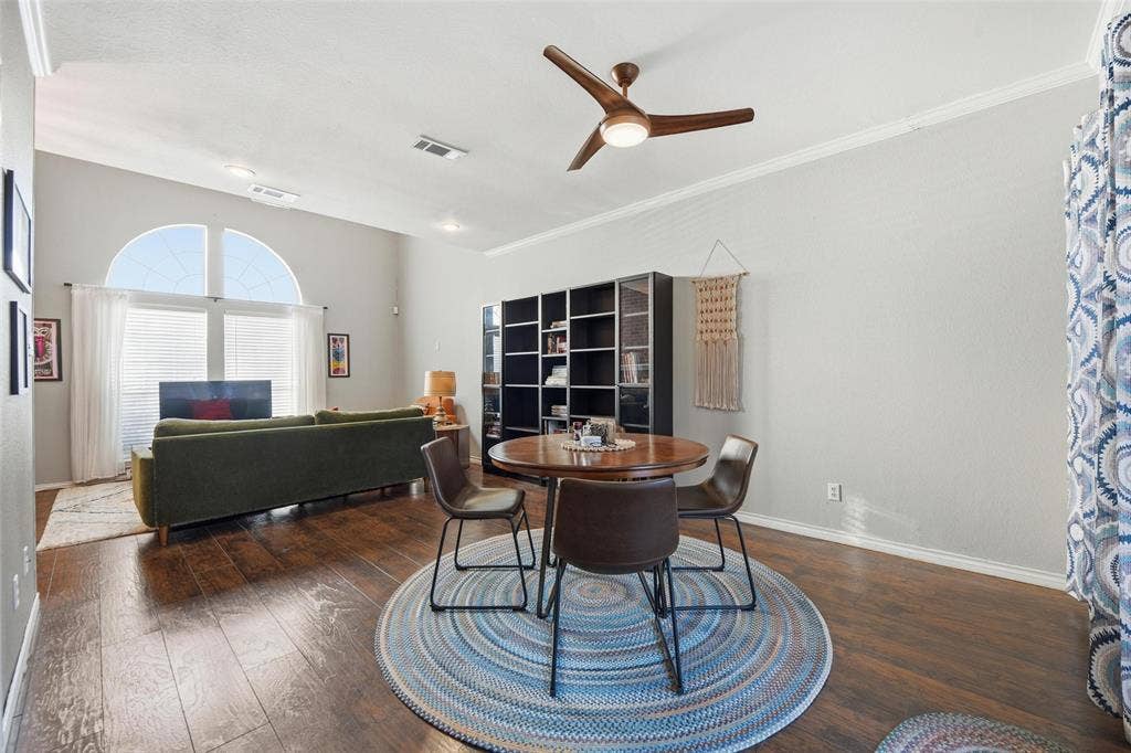 Spacious living area featuring wood-finish flooring, vaulted ceilings, and crown molding