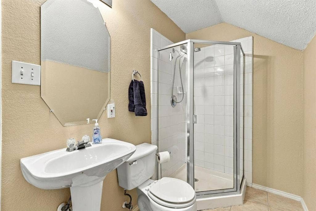 103 Deerpath Road, Hickory Creek, TX 75065 Pedestal sink, wall-mounted mirror, stand-up shower with glass enclosure, white toilet, and neutral wall tones