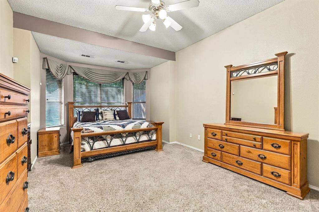 103 Deerpath Road, Hickory Creek, TX 75065 Tray ceiling with recessed beam, ceiling fan with integrated lighting, carpeted flooring, and a bay window