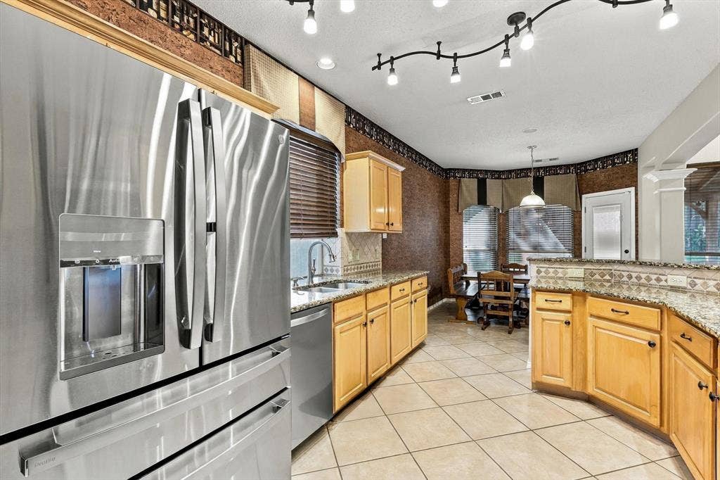 103 Deerpath Road, Hickory Creek, TX 75065 Stainless steel French door refrigerator, granite countertops, tile backsplash, light wood-finish cabinetry, and track lighting