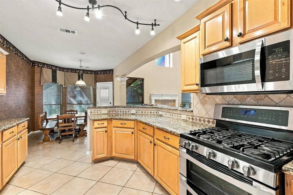 103 Deerpath Road, Hickory Creek, TX 75065 Kitchen featuring light wood cabinetry, stone countertops, stainless steel appliances, tile flooring, and track lighting