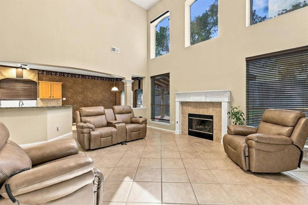 103 Deerpath Road, Hickory Creek, TX 75065 Spacious open-concept living area featuring soaring ceilings with clerestory windows, neutral tile flooring throughout, a built-in fireplace with surround, and multiple recessed lighting fixtures