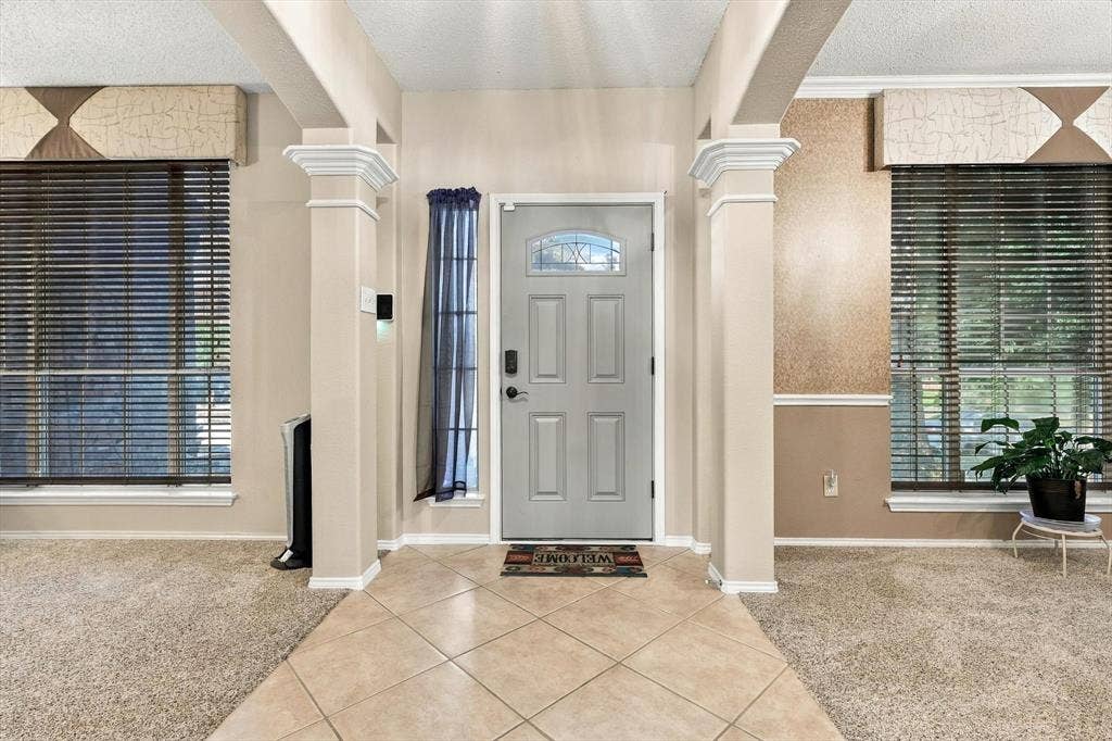 103 Deerpath Road, Hickory Creek, TX 75065 Entryway featuring tile flooring, decorative architectural columns, and a paneled door with an arched glass insert
