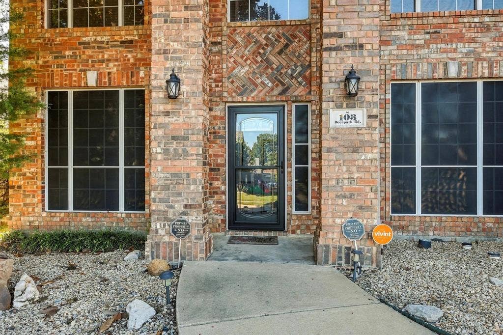 103 Deerpath Road, Hickory Creek, TX 75065 Brick exterior with decorative brickwork accents, multiple windows with white framing, and a central entry door with a sidelight