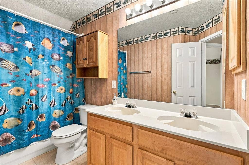 103 Deerpath Road, Hickory Creek, TX 75065 Dual sink vanity with light wood-finish cabinetry, a large wall-mounted mirror, and overhead vanity lighting