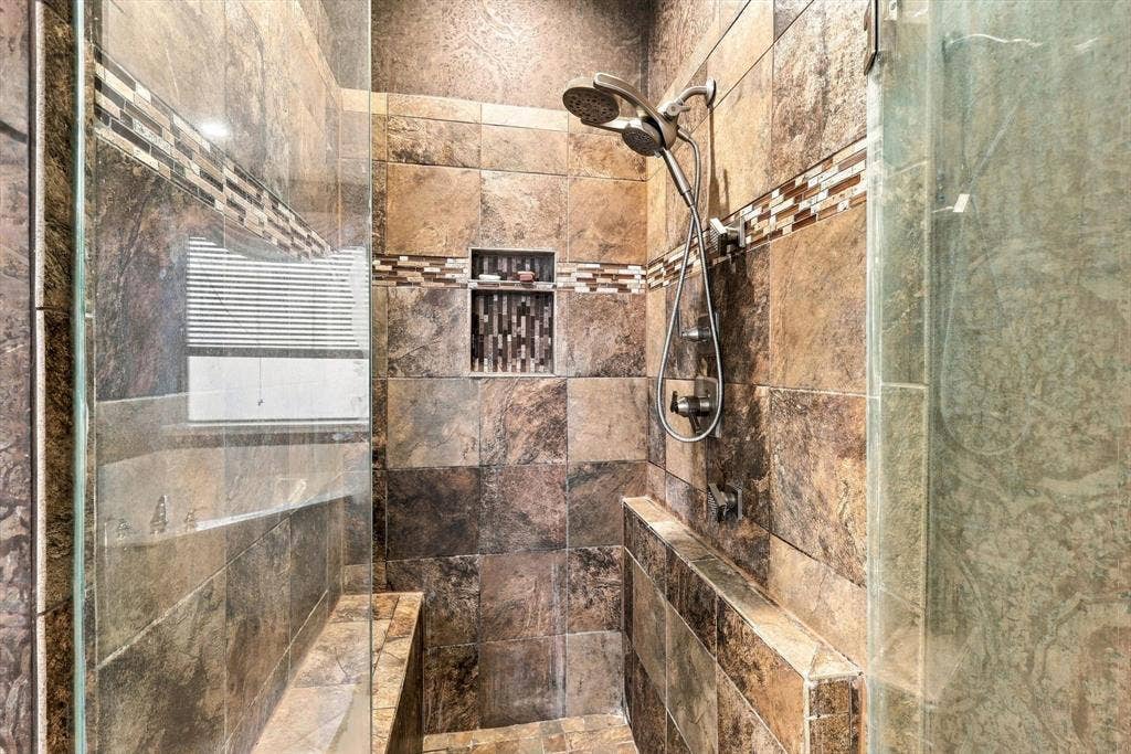 103 Deerpath Road, Hickory Creek, TX 75065 Tiled walk-in shower featuring a built-in bench, recessed shelf, and dual shower heads