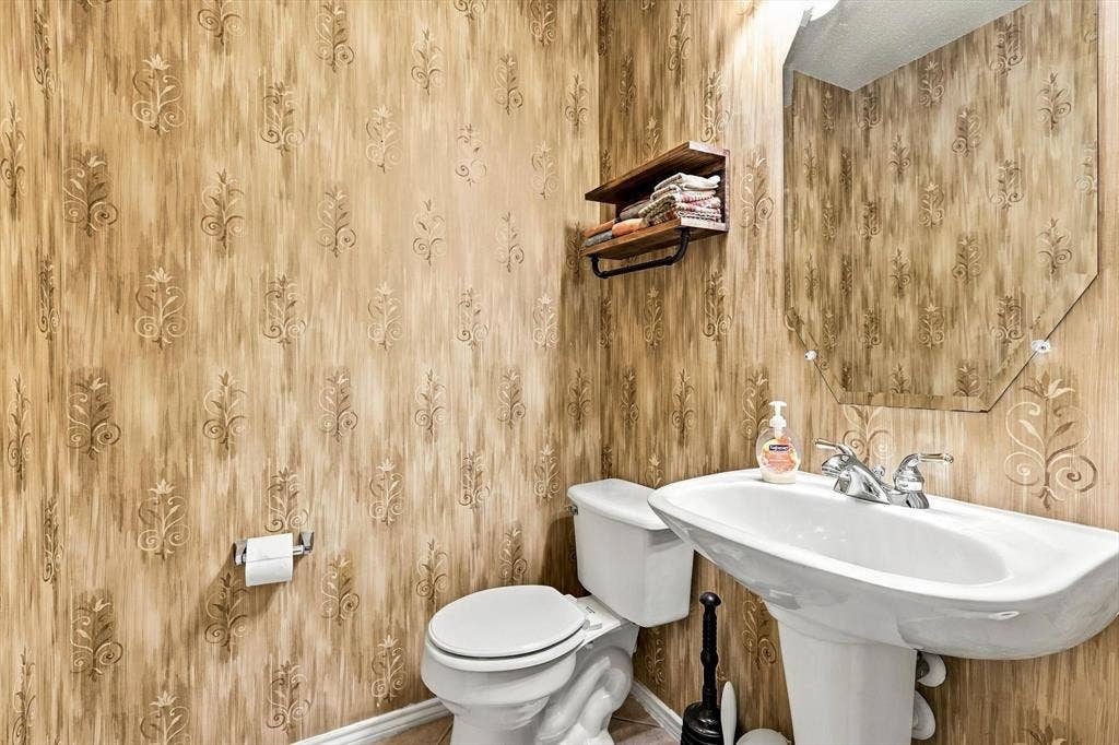103 Deerpath Road, Hickory Creek, TX 75065 Pedestal sink with dual-handle faucet, wall-mounted mirror, and decorative wallpaper