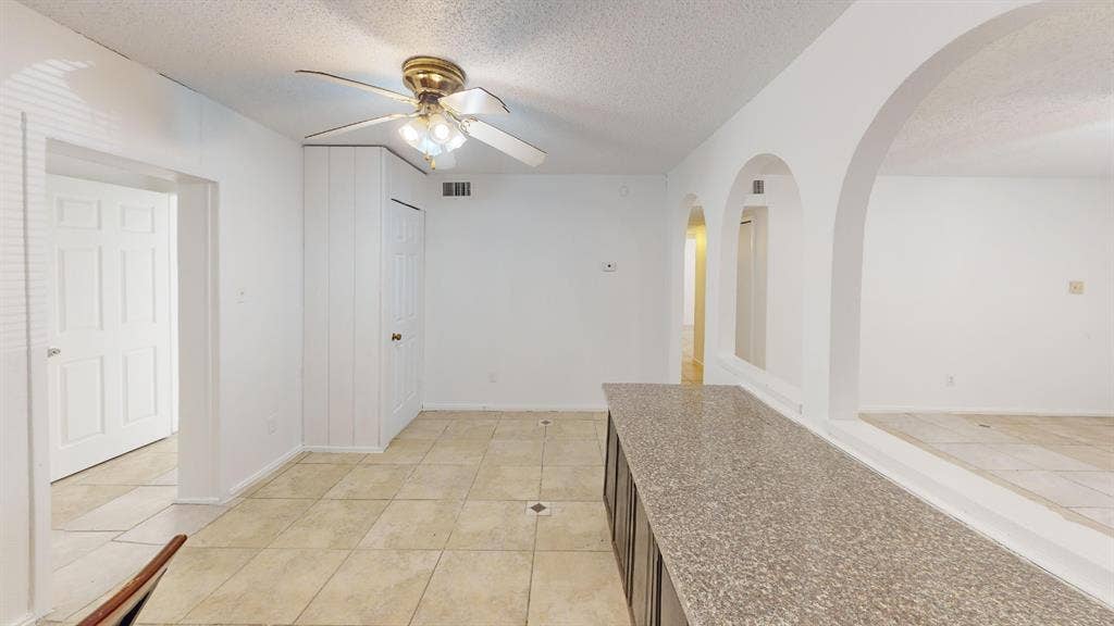 1710 Meridian Way, Garland, TX 75040 Tile flooring, built-in cabinetry with a stone-finish countertop, arched room openings, and a ceiling fan with integrated lighting