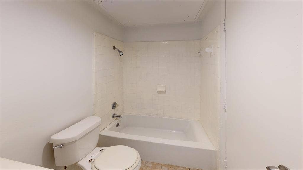 1710 Meridian Way, Garland, TX 75040 White porcelain toilet and bathtub with tiled shower surround