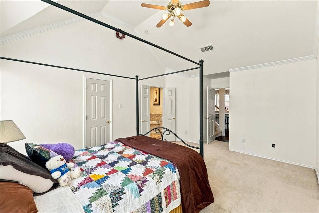Vaulted ceiling with a ceiling fan, crown molding, and neutral-toned carpet flooring
