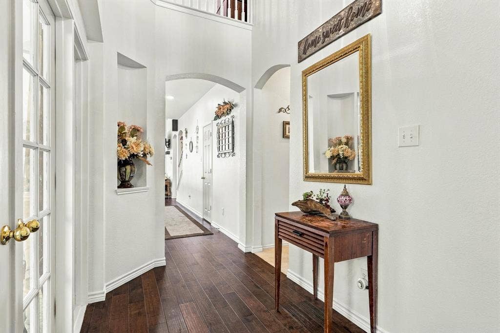 Hardwood flooring throughout, arched doorways, white interior walls, and a built-in wall niche