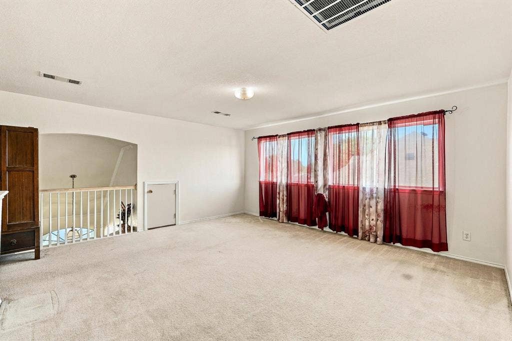 Carpeted room with multiple windows, recessed lighting, and a white railing