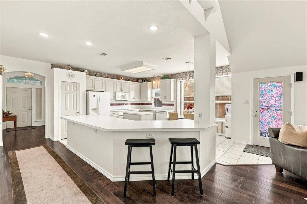 Kitchen featuring white cabinetry, white appliances, a center island, and recessed lighting