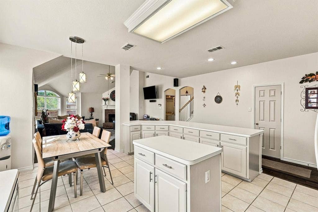 Kitchen featuring an island, white cabinetry, light-toned tile flooring, and recessed lighting