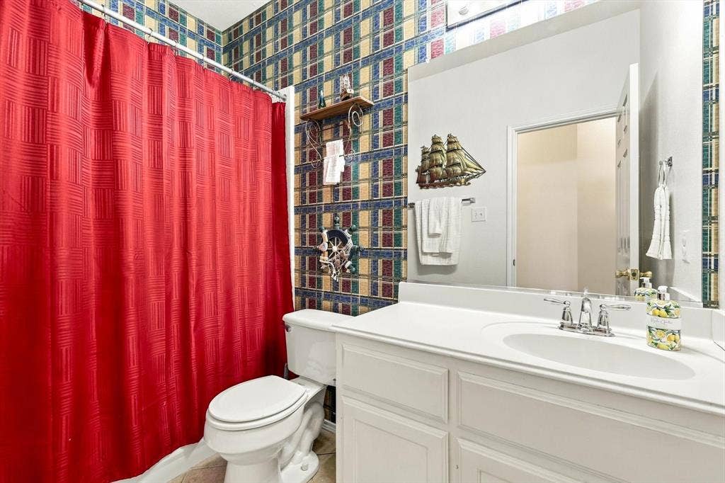 White vanity with a single basin sink, chrome faucet, and expansive wall-mounted mirror