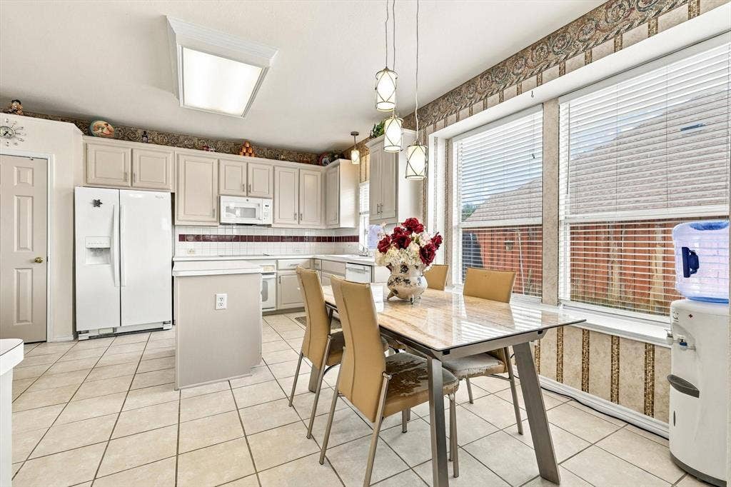 Kitchen with tile flooring, white cabinetry, white appliances, and a tiled backsplash